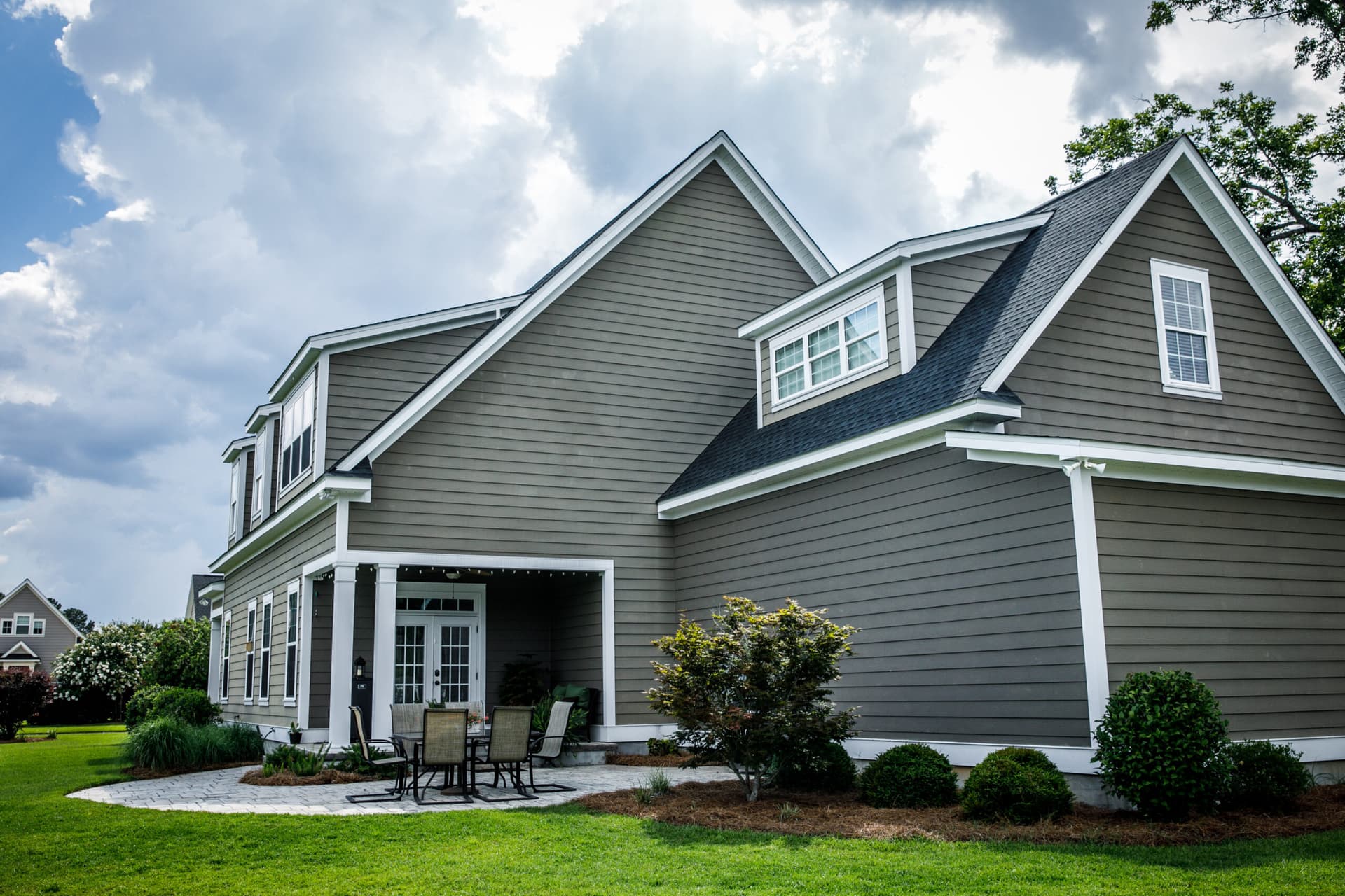Two-storey home with taupe siding, white trim and a dark shingle roof