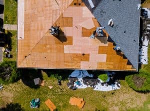 Aerial view of a roof replacement with shingles stripped back to bare decking on one slope